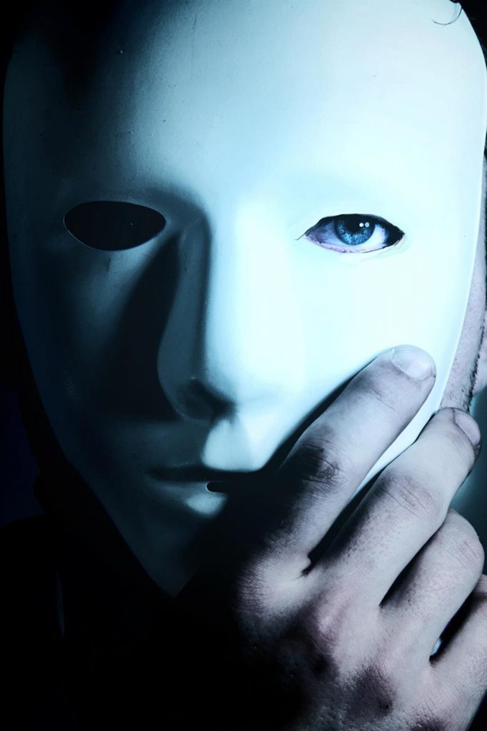 Gros plan sur une rĂ©dactrice web et SEO cachant son visage derriĂšre un masque blanc, illustrant le syndrome de lâimposteur chez les freelances.