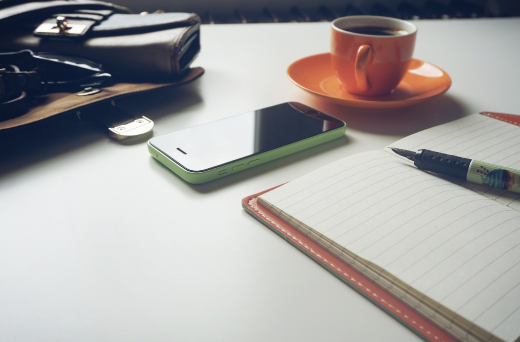 Bureau de travail avec carnet ouvert, stylo, smartphone et tasse de café — symboles d'une rédaction d'un contenu web éthique et authentique.