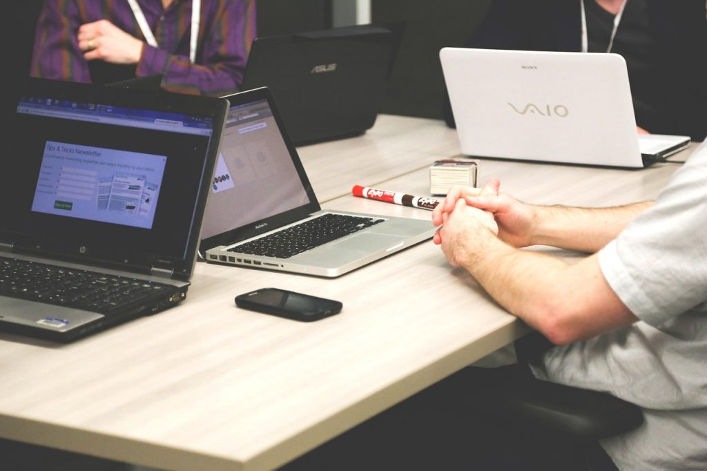Personnes en réunion autour d’une table avec des ordinateurs portables, en train de travailler sur une content campaign